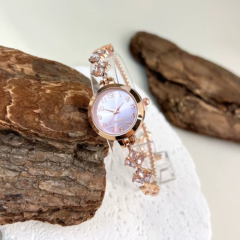Montre élégante pour femme à quartz : boîtier rond en alliage, cadran classique à chiffres arabes, bracelet tendance orné de diamants et aiguilles en forme de feuille.