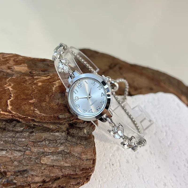 Montre élégante pour femme à quartz : boîtier rond en alliage, cadran classique à chiffres arabes, bracelet tendance orné de diamants et aiguilles en forme de feuille.
